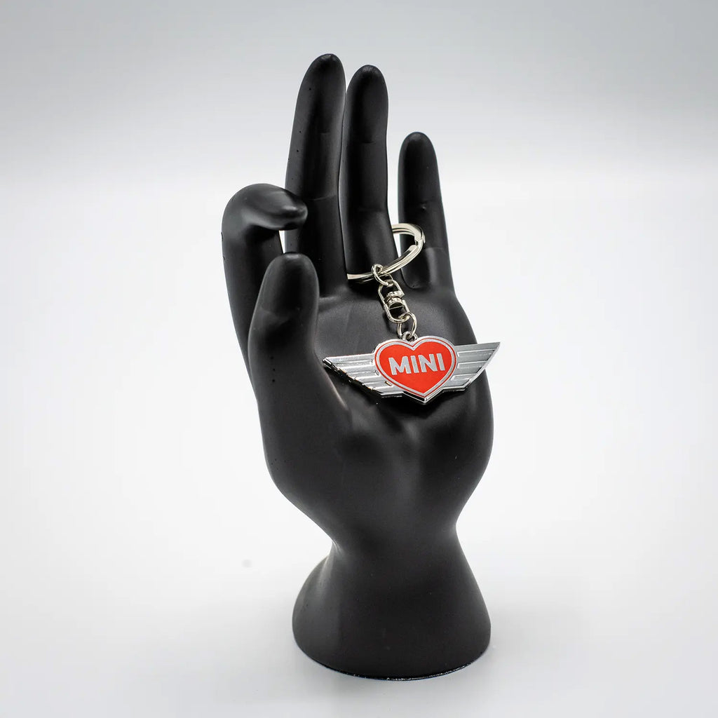 Keychain with a Chili Red MINI heart design on a black mannequin hand against a white background.