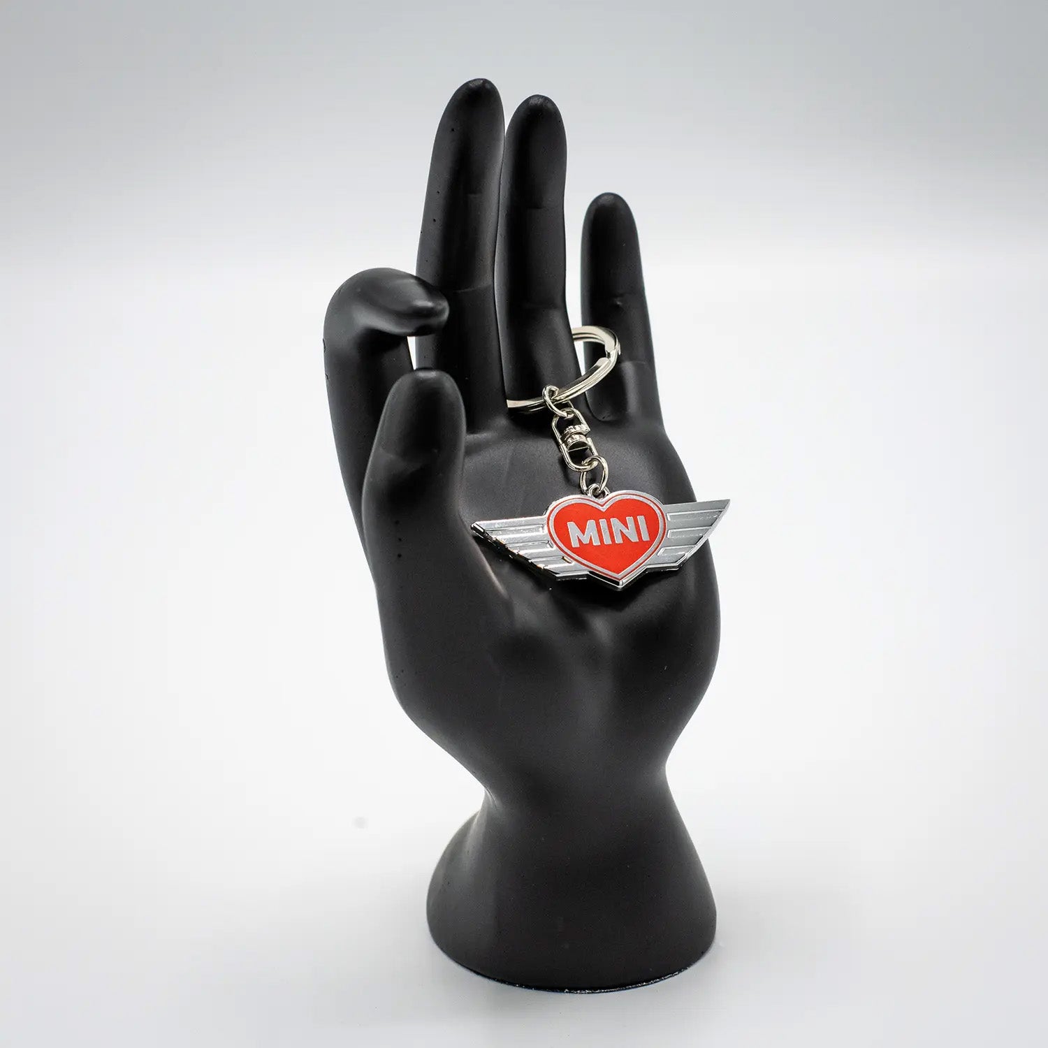 Keychain with a Chili Red MINI heart design on a black mannequin hand against a white background.