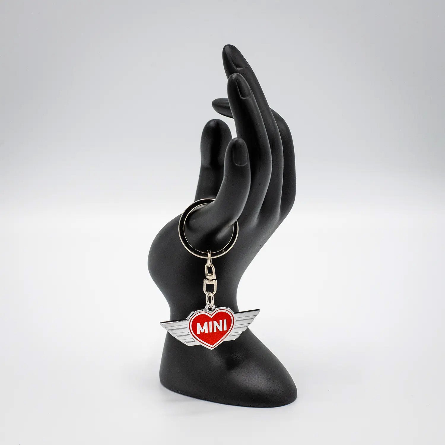 Keychain with a Chili Red MINI heart design on a black mannequin hand against a white background.