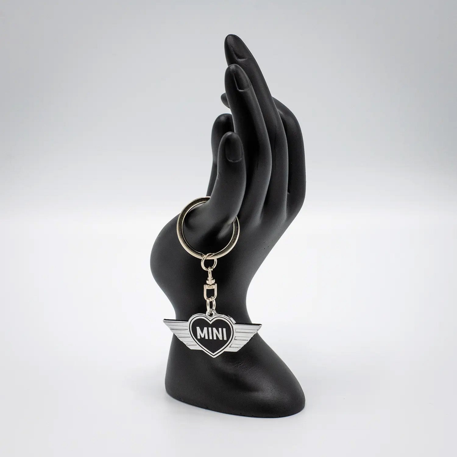 Keychain with a Jet Black MINI heart design on a black mannequin hand against a white background.