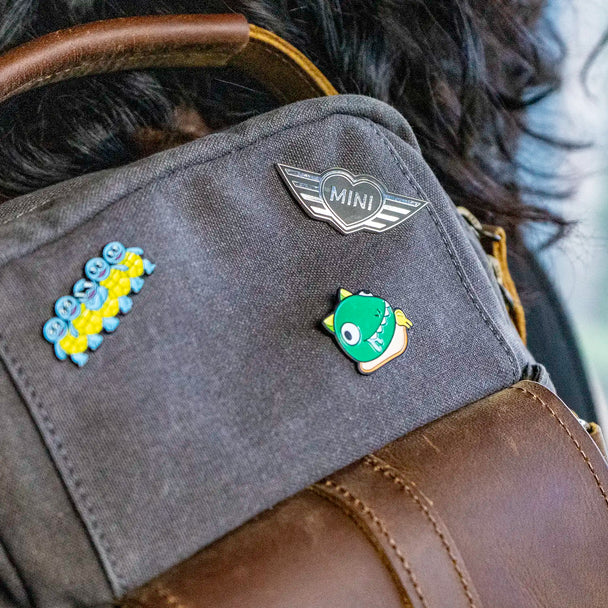 Close-up of a MINI Heart pin on a messenger bag.