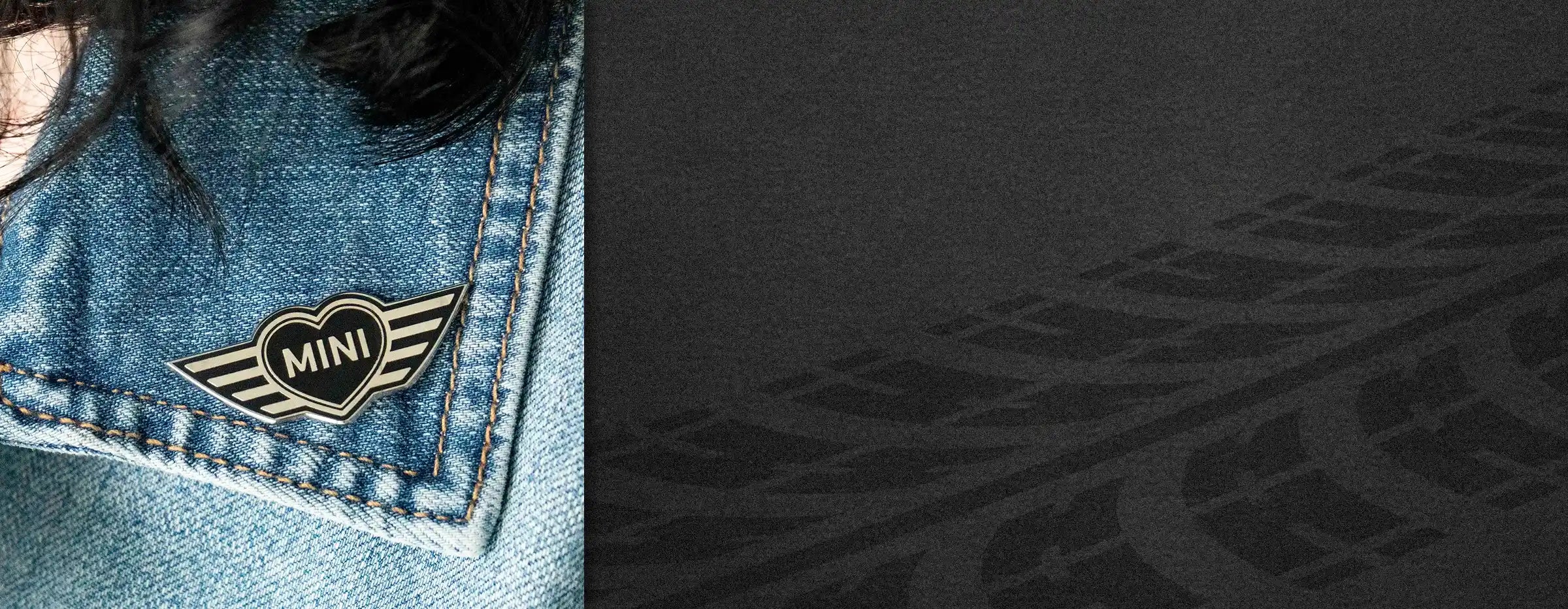 MINI heart wing enamel pin worn on a denim jacket, shown against a dark textured background.