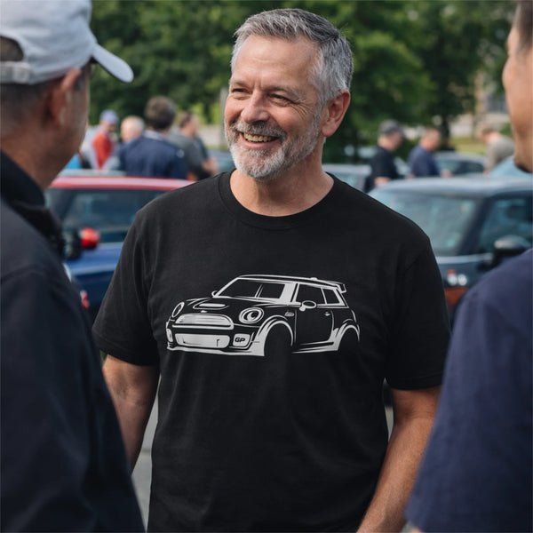 A man at a MINI Cooper meet-up wearing a black t-shirt with a white R53 GP gesture sketch design talking with two people.