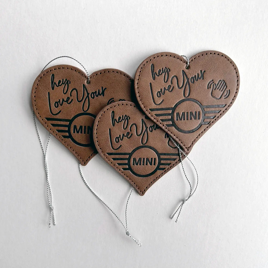 Three Leather MINI Love Ducking Ornaments with ‘Hey, Love Your MINI’ debossed design on a light gray background.