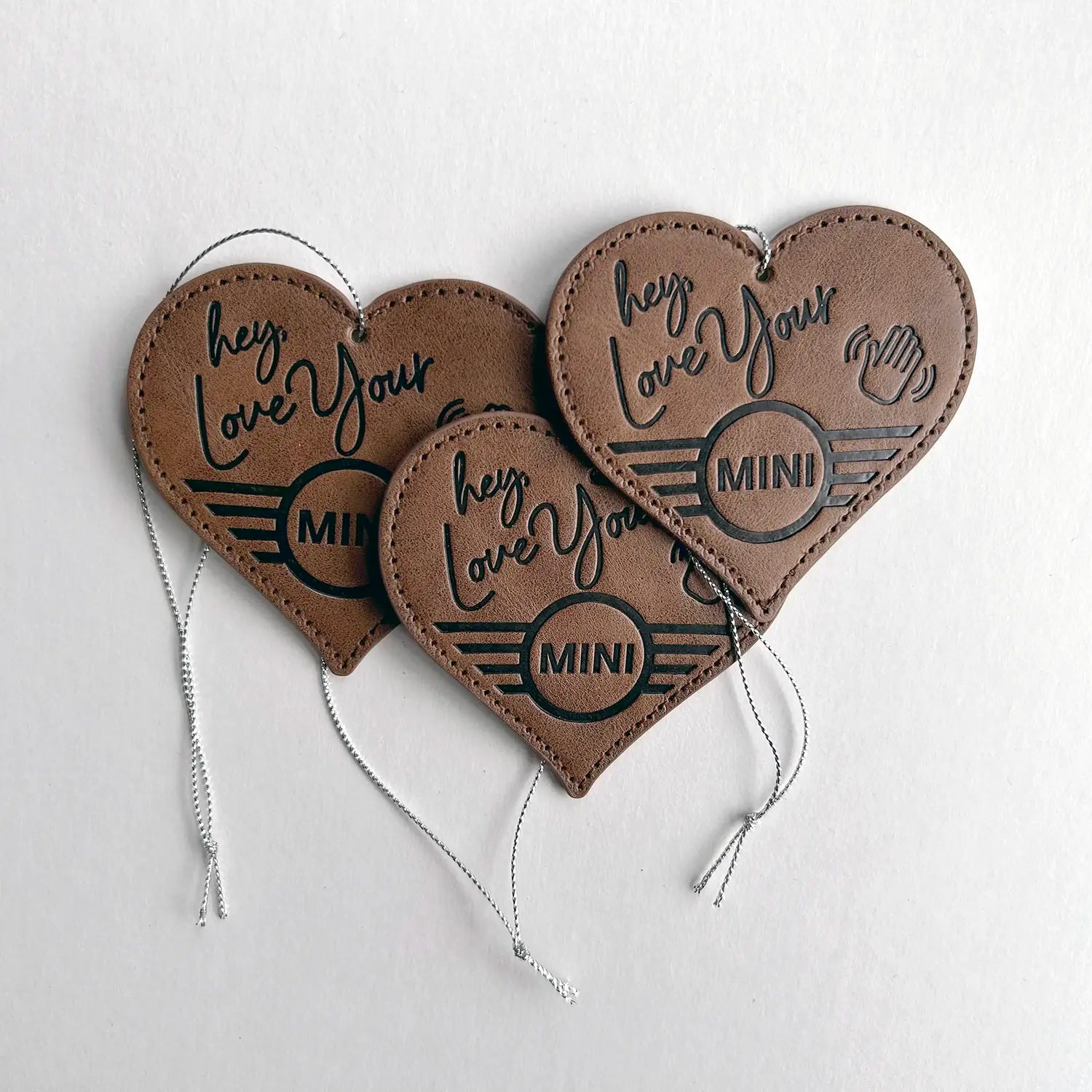 Three Leather MINI Love Ducking Ornaments with ‘Hey, Love Your MINI’ debossed design on a light gray background.