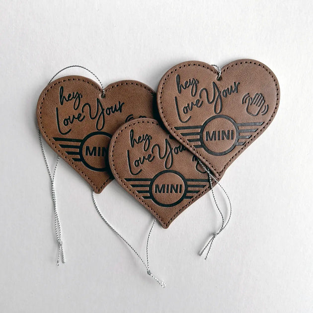 Three Leather MINI Love Ducking Ornaments with ‘Hey, Love Your MINI’ debossed design on a light gray background.
